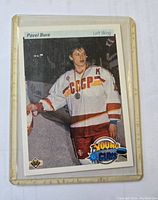 Front of Pavel Bure rookie card showing him in USSR jersey with Young Stars logo, inside plastic protective case showing wear and discoloration.