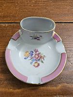 Top view showing the white porcelain ashtray with built-in lighter holder, floral decoration and pink gold-trimmed details.