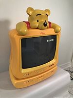 Front view of yellow CRT TV/DVD player with Winnie the Pooh head, screen displaying 'VIDEO1'