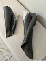 Photo showing two vintage Hilborn Pottery pocket vases, one smaller and one larger, both black matte with white accent folds.