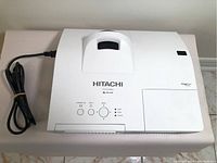 Top view of white Hitachi CP-D32WN LCD projector showing control buttons and power cable.