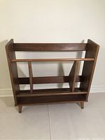 Front view of MCM walnut bookcase showing open frame and lower shelf