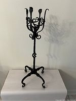 Front view of the vintage hand forged wrought iron plant stand with decorative curled hooks and legs