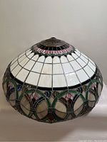 Front view of Tiffany style stained glass lamp shade showing white, pink, green, and black stained glass panels with a metal vented top.