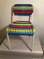 Front view of vintage IKEA Fargglad children's chair showing woven seat and back in blue, red, yellow, and green stripes with white metal frame