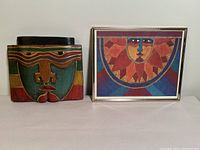 Full view of wooden mask alongside framed Laurel Burch print showing both items in lot.