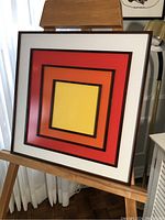 Front view of geometric wood wall art showing nested colored squares and frame.