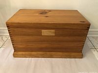 Front view of the pine wood storage box showing dovetail joints and wood grain detail.