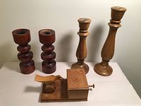 Four wooden candle holders and a hand carved wooden cigarette dispenser with floral design and lever seen from front.