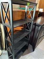 Full view of black metal bookshelf showing four shelves and X-shaped side supports.