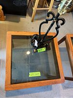 Close-up of one mid-century side table from the lot showing wooden frame and glass top in detail, with one black metal table lamp on top.