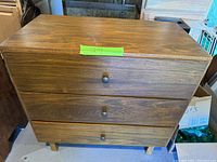 Front view of the small wooden dresser with three drawers and round wooden knobs.