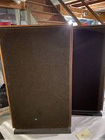 Pair of Realistic speakers shown with front black fabric grilles, wooden side panels, and black base.