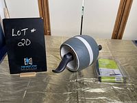 Photo showing the abdominal roller with curved handles beside the packaged Therastretch resistance band on a table.