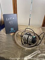 Aerator device laid out flat with hose coiled, showing front and attached cable.