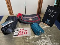 Overview of all four lot items on table: Paul Frank bag, down footwear packaging, turquoise zippered pouch, and canvas pouch with text.