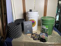 Photo of Bountea compost tea brewing kit components including white and green buckets, black bubbler bags, nutrient packets, compost bags, and tubing set on a table