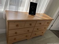 Front view of the dresser showing six drawers with round wooden knobs and flat top surface.