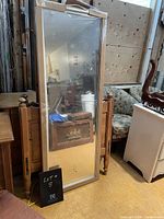 Full length mirror with silver-colored frame standing vertically, showing the reflective surface and frame details.