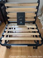 IKEA futon chair frame showing black metal base with wooden slats in open chair position.