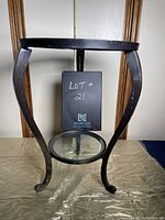 Front view of the table showing the curved metal legs, the bottom glass shelf, and the central support pole.