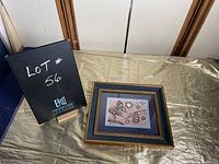 Photo of entire framed painting on a table with lot sign next to it
