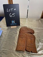 Photo of Haida style wooden carving on display table with lot number sign