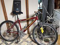 Side view of the red Rocky Mountain Oxygen Race mountain bike showing frame, wheels, and handlebars indoors.