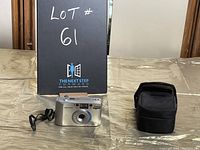 Lot 61 board with Pentax silver camera and black Optex camera case on table