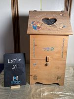 Full front view of wooden potato/onion bin with folk art designs, heart cutout lid, and metal mesh