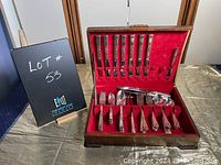 Full view of cutlery set in open vintage red velvet-lined wooden case showing knives, forks, spoons, and broken case clasp.