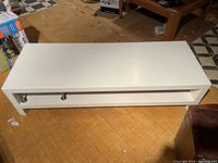 Top and front view of white modern TV stand showing structure and surface condition