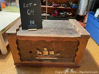 Front and top angled view of the antique wooden chest showing carved ship design on front panel and scalloped edges on top and front.