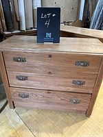 Front view of the three drawer wooden dresser labeled as lot 4, showing wood grain and metal handles