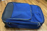 Closed blue Eagle Creek suitcase showing front zippered pockets and slipaway luggage tag