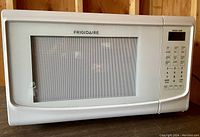 Front view of white Frigidaire countertop microwave oven with closed door and control panel visible.