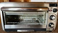 Front view of Hamilton Beach toaster oven showing control knobs and glass door with handle.