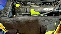 Close-up of Rockwell Sonicrafter F30 oscillating tool inside open black and green carrying bag, showing tool grip, cord, and branding