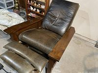 Front view of Stickley Spindle Morris recliner with extended footrest showing leather cushion and oak armrests