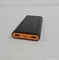 Front view showing two USB output ports, micro USB input port, and four LED battery indicator lights on an orange panel.