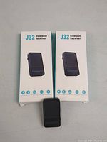 Two boxed J32 Bluetooth receivers with one device out of the box shown in front.