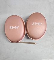Rosy gold hard shell carrying cases for Bluetooth headphones with ZIHNIQ logo, front view