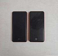 Front view of two black power banks with orange sides, showing the power buttons