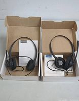 Two wired Plantronics HW261n office headsets with single ear cushions and boom microphones in open brown boxes, showing headsets and instruction sheets inside.