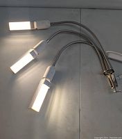 Three LED grow light heads illuminated, attached to flexible gooseneck arms and clamp base.