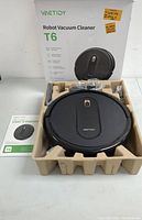 Robot vacuum cleaner and accessories in packaging showing vacuum, box, and user's manual.