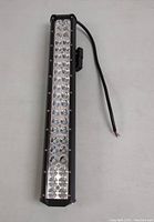 Front-angle photo of 20-inch LED truck light bar showing LED bulb arrangement, black metal housing, mounting bracket, and wiring cable with exposed wire ends.