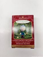 Photo of sealed Hallmark Keepsake box featuring Charlie Brown ornament dressed in winter clothing, labeled as second ornament in a five-piece Christmas collection