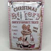 Full view of the Christmas bakery sign showing text and festive illustrations of cupcakes and gingerbread men, with pink gingham border.