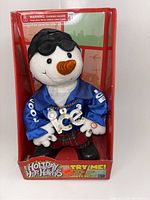 Full view of Holiday Hip Hoppers snowman plush toy inside original packaging, showing details of outfit and face.